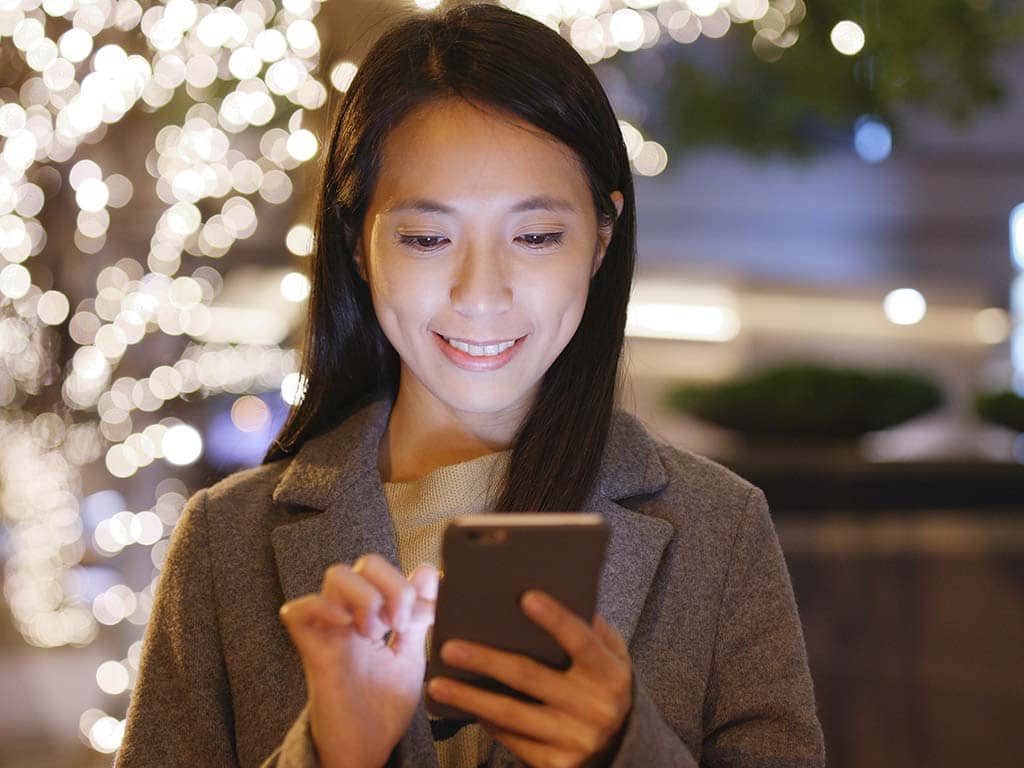 woman smiling while using phone