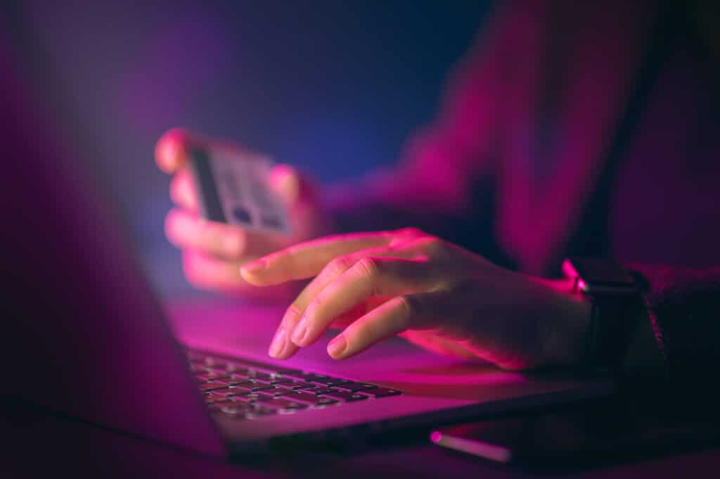 woman at her laptop with credit card in hand representing dangers in cybersecurity