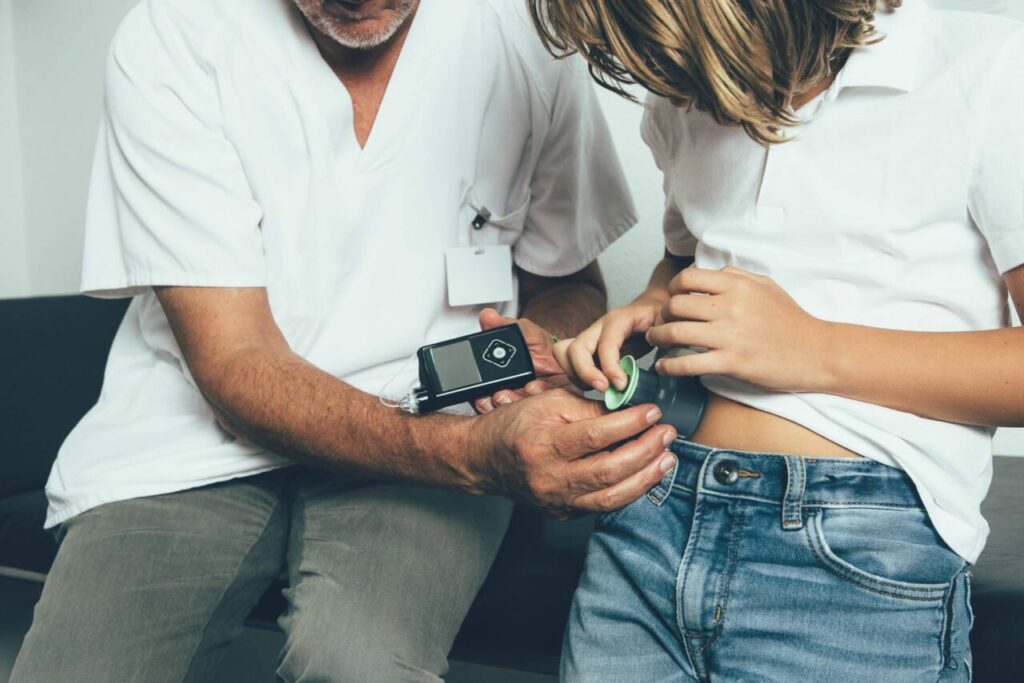 doctor teaching young patient to use insulin pump medical device